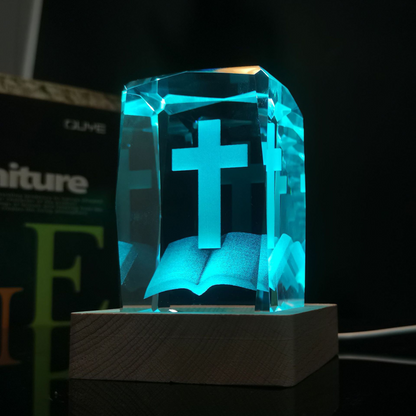 Cruz de cristal iluminada en tono turquesa sobre base de madera