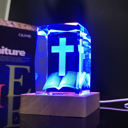 Cruz de cristal iluminada en tono azul sobre base de madera